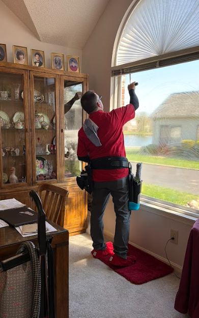 Shine technician cleaning an interior arched window with shoe covers on carpet